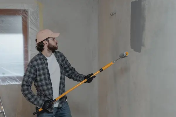 Painter rolling grey paint onto an interior wall in Worcester